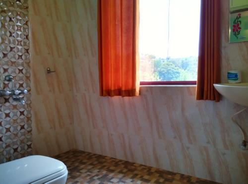 a bathroom with a toilet and a window at Panthalams Homestay in Thekkady