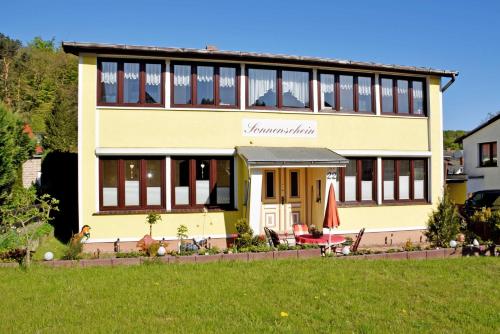 una casa amarilla con césped delante en Haus Sonnenschein, en Ostseebad Sellin