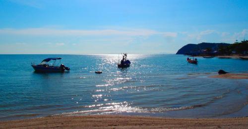 three boats in the water on a beach at Tea Moon Beach House in Thongsala