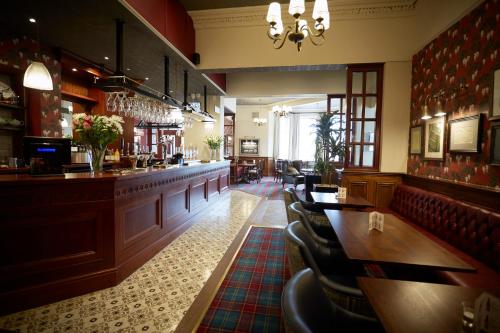 a bar with tables and chairs in a restaurant at Gwesty Links in Llandudno