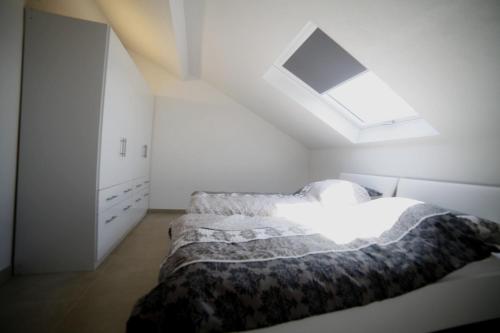 a white bedroom with a bed and a skylight at Passivhaus 750m vom Bodensee -- 2x E-bike inklusive -- Neubau 2019 am Ortsrand in Öhningen