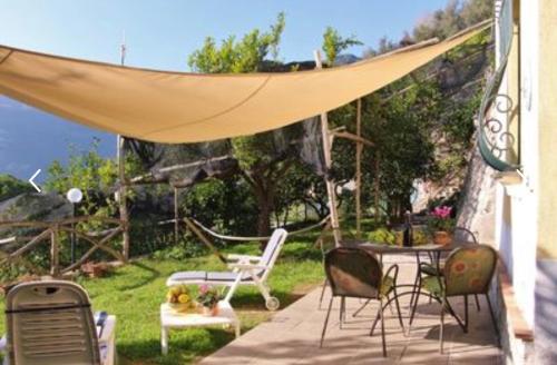 eine Terrasse mit einem Tisch und Stühlen unter einem Zelt in der Unterkunft Casa Ortensia in Minori