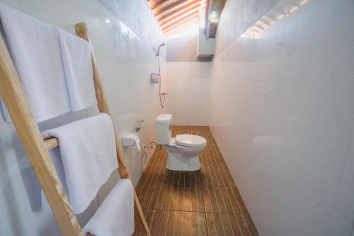 een badkamer met een toilet en handdoeken op een houten vloer bij Pi Karya Beach in Nusa Penida