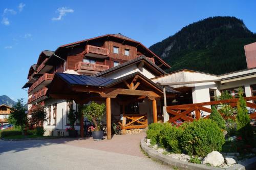 a large wooden building with a mountain in the background at Hallstatt Dachstein Inn in Gosau