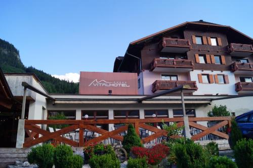 a hotel in the mountains with a fence and flowers at Hallstatt Dachstein Inn in Gosau