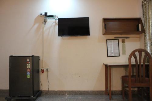 a room with a refrigerator and a television on the wall at YWCA International Centre in Mumbai