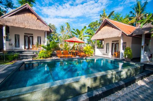 a villa with a swimming pool in front of a house at Japa Bungalow in Nusa Penida