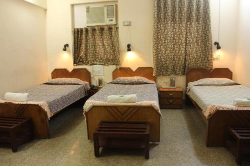 a room with three beds and a mirror at YWCA International Centre in Mumbai