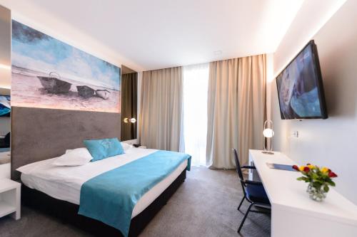 エフォリエ・ノルドにあるMirage Medspa Hotelのベッドとデスクが備わるホテルルームです。