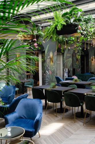 a restaurant with tables and chairs and plants at Hotel Atrium in Kraków