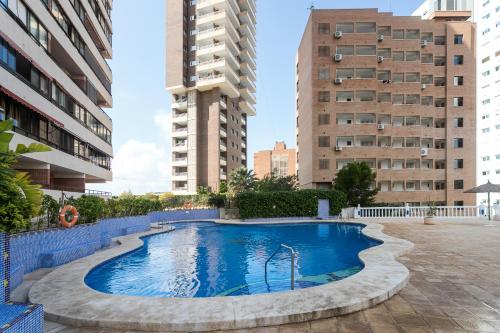 a swimming pool in the middle of two tall buildings at LuxBenidorm in Benidorm