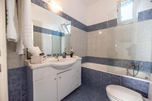 een badkamer met een wastafel, een bad en een toilet bij Stegna Bay Apartment in Archangelos