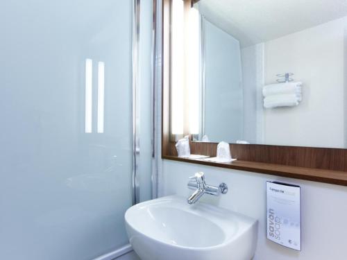 y baño con lavabo blanco y espejo. en Campanile Montpellier Est Le Millénaire, en Montpellier