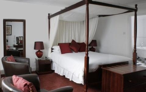 a bedroom with a canopy bed and a desk at Thanington Hotel in Canterbury