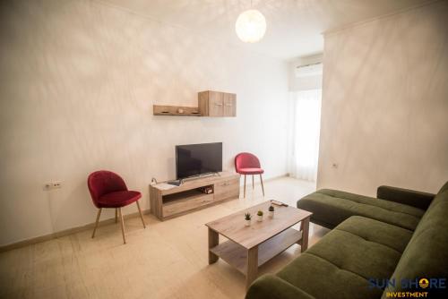 sala de estar con sofá verde y 2 sillas rojas en Explore Greece from Close the Sea Apartment, en Chalkida