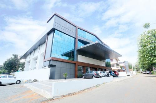 a large glass building with cars parked in front of it at Sunstar Residency & Food Plaza Pala in Lālam