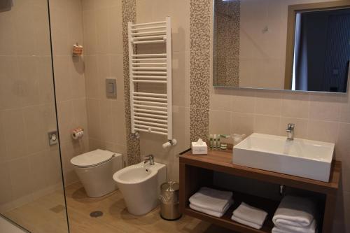 ein Badezimmer mit einem Waschbecken, einem WC und einem Spiegel in der Unterkunft Hotel Commercio in Battipaglia