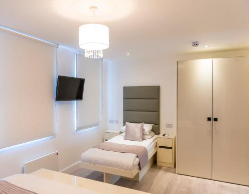 a small bedroom with a bed and a tv on the wall at Messina Studios in London