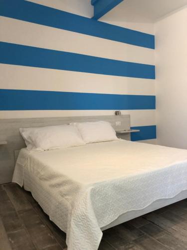 a bed with a blue and white striped wall at Borgo Albador Rooms in Posada