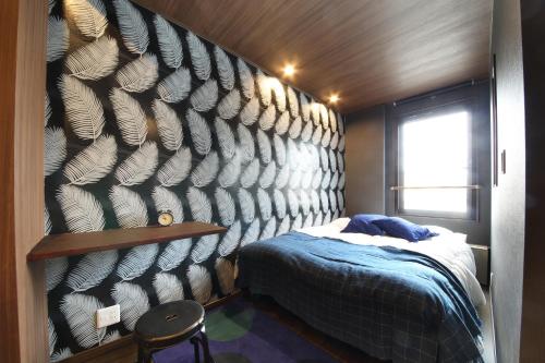 a bedroom with a wall with a bed and a chair at s-rea TOKYO301 in Tokyo
