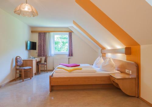 a bedroom with a bed and a desk and a window at Weinhotel Wachau in Spitz