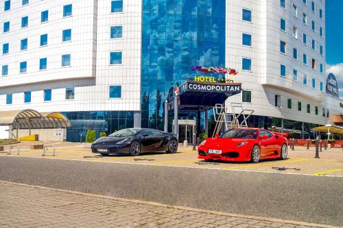 due auto parcheggiate in un parcheggio di fronte a un edificio di Cosmopolitan Bobycentrum - Czech Leading Hotels a Brno