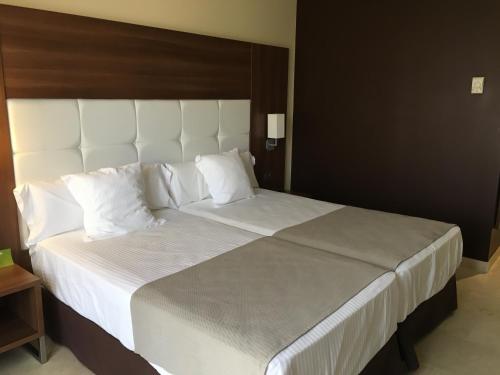a large bed with white sheets and pillows at Spa Jardines de Lorca in Lorca