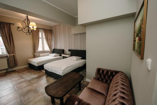 a hotel room with two beds and a couch at Apartamenty Kuźnia in Ełk