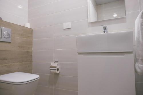 a white bathroom with a toilet and a sink at The Stay Furnished Apartments in Dbayeh