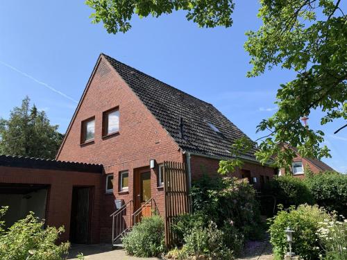 een rood bakstenen huis met een zwart dak bij Haus Plüschmors in Garding