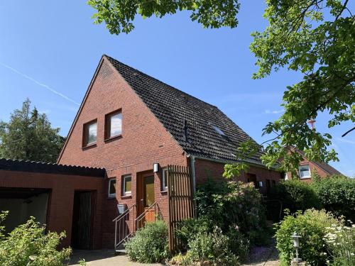 ein rotes Backsteinhaus mit schwarzem Dach in der Unterkunft Haus Plüschmors in Garding