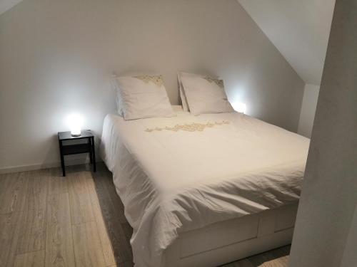 een bed met witte lakens en kussens in een kamer bij Au domaine des roches in Saint-Pierre-sur-Dives