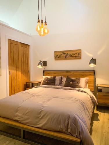 a bedroom with a large bed with a wooden headboard at Balloan Cottage Cowshed in Inverness