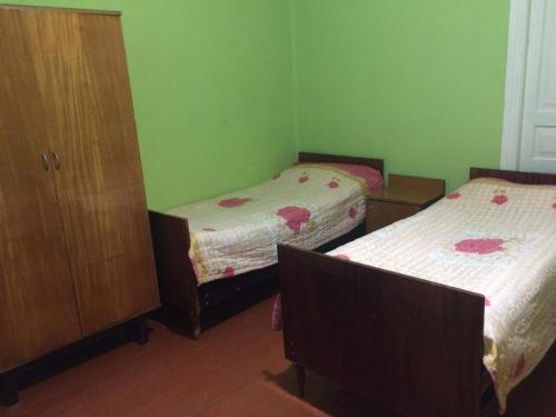 a green room with two beds and a cabinet at GuestHouse Malkhazi in Borjomi
