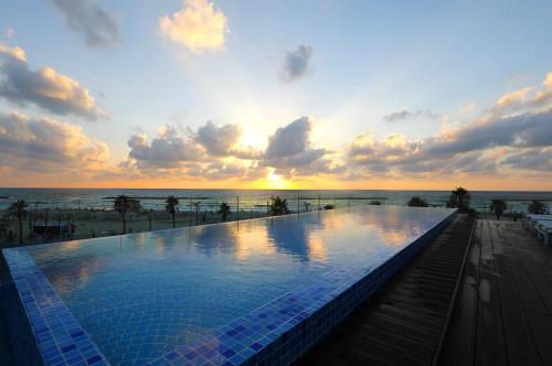 uma piscina na praia ao pôr do sol em Herbert Samuel Opera Tel Aviv em Tel Aviv