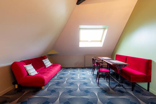 Cette chambre comprend un canapé rouge, une table et des chaises. dans l'établissement Maison Longuevie, à Amiens