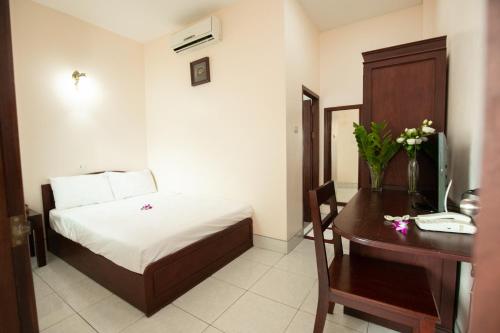a bedroom with a bed and a desk with a computer at Hoang Kim Hotel in Vientiane