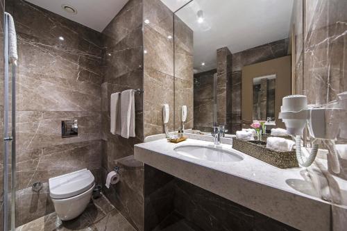 a bathroom with a sink and a toilet and a mirror at Redmont Hotel Nisantasi in Istanbul