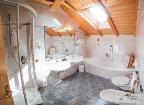 a bathroom with two sinks and a tub and a toilet at Hotel Pra Tlusel in Selva di Val Gardena