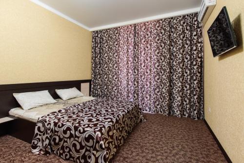 a small bedroom with a bed and a curtain at Hotel Seven in Lazarevskoye