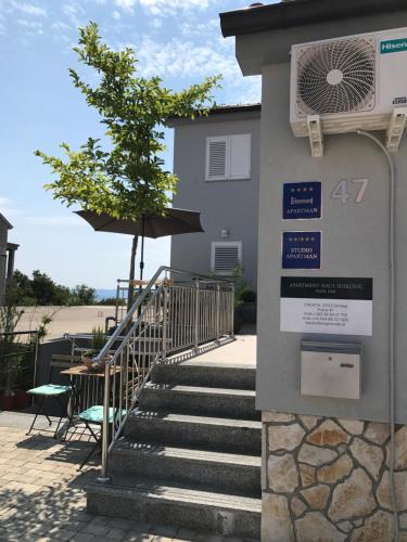 a building with stairs and an umbrella and a sign at Apartmenthaus Suskovic Insel Krk in Omišalj