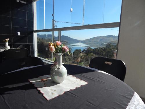 a vase with flowers on a table with a view at Pousada Do Alto in Capitólio