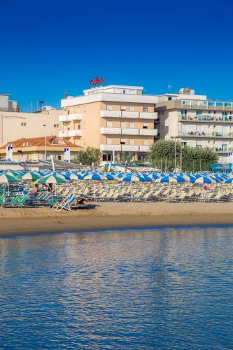 a beach with chairs and umbrellas and a building at Hotel Touring in Misano Adriatico