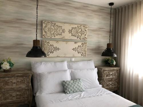 a bedroom with a white bed with two lamps at Casa do Castelo in Sernancelhe