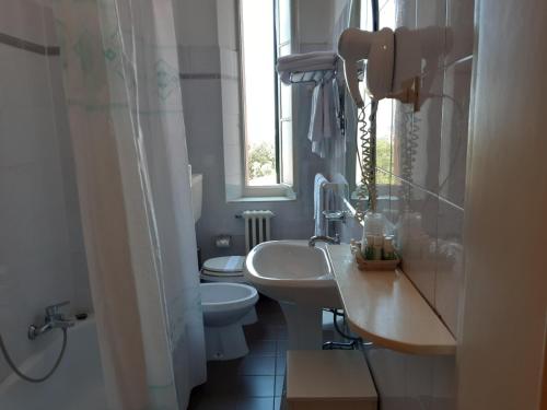 łazienka z umywalką, toaletą i oknem w obiekcie Hotel Italia w mieście Marina di Massa