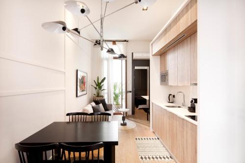 a kitchen and dining room with a black table and chairs at Casa Noa Apartments in Seville