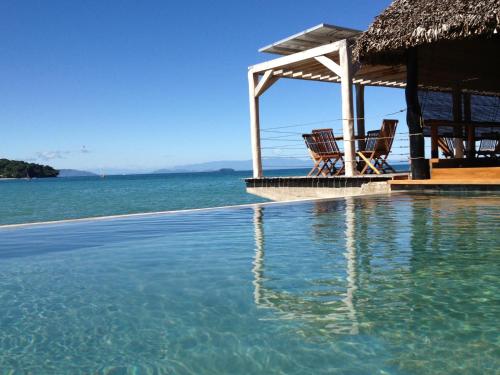 a swimming pool with a gazebo and the water at L'heure Bleue in Ambatoloaka