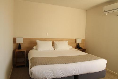 ein Schlafzimmer mit einem Bett mit weißen Laken und Kissen in der Unterkunft Hotel Umawue in Concepción