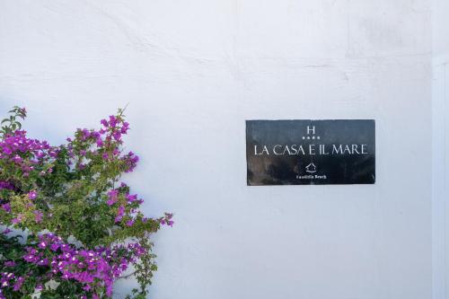 a sign on a white wall next to flowers at La Casa E Il Mare, Private Bay Hotel in Mattinata