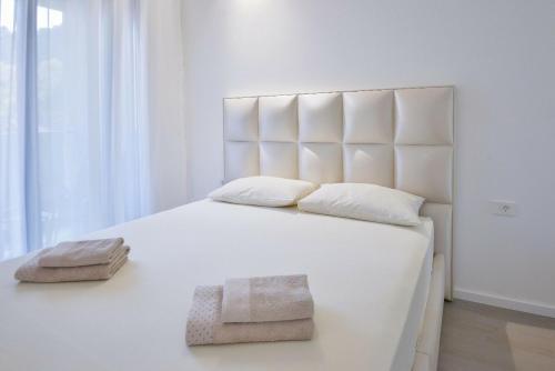 a bedroom with a large white bed with two towels on it at LUKA in Budva